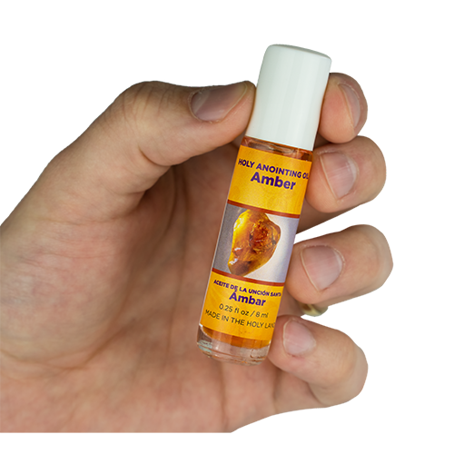 view of amber scented anointing oil being held in a human hand