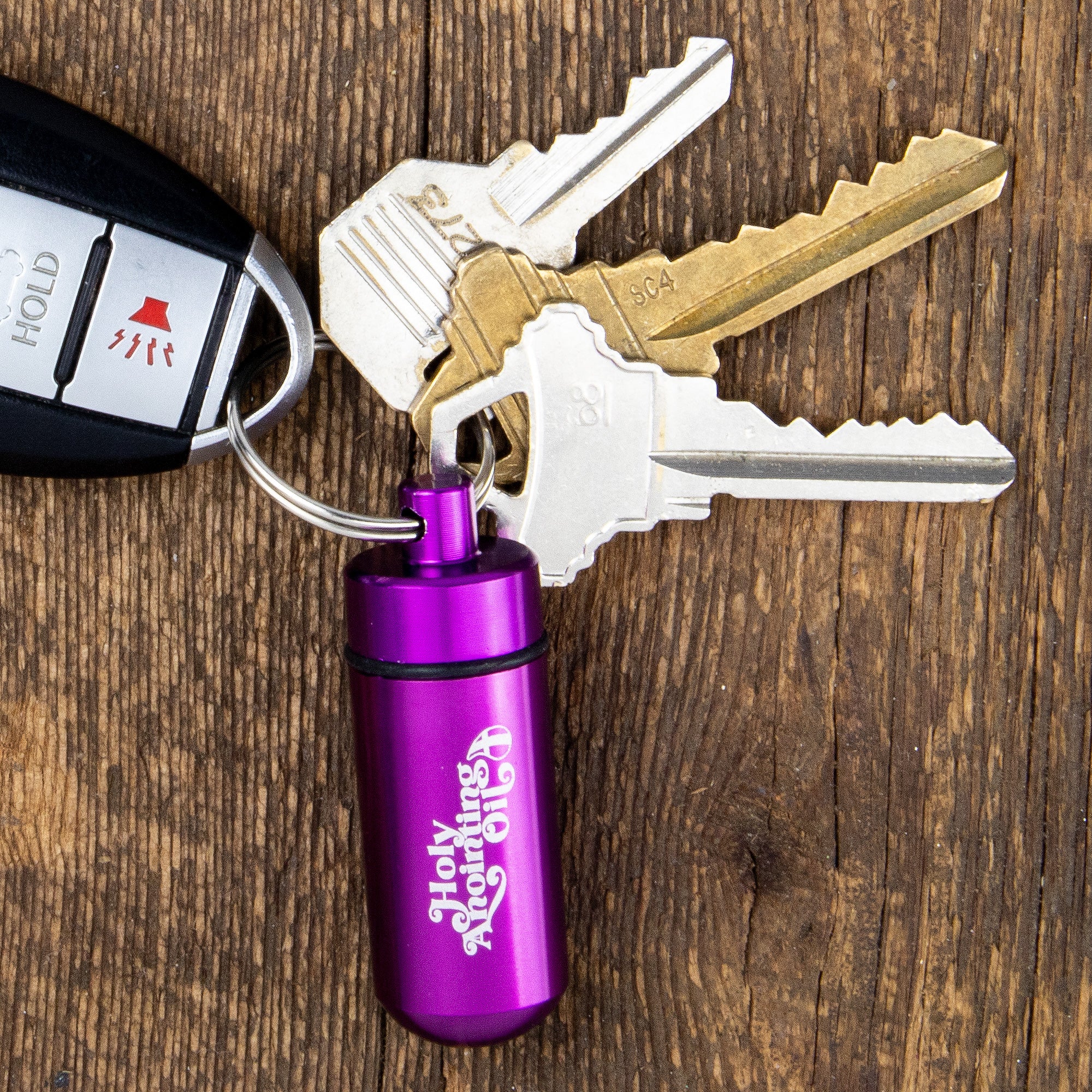 Oil Vial Keyring showing keyring vial holder with keys on wood background