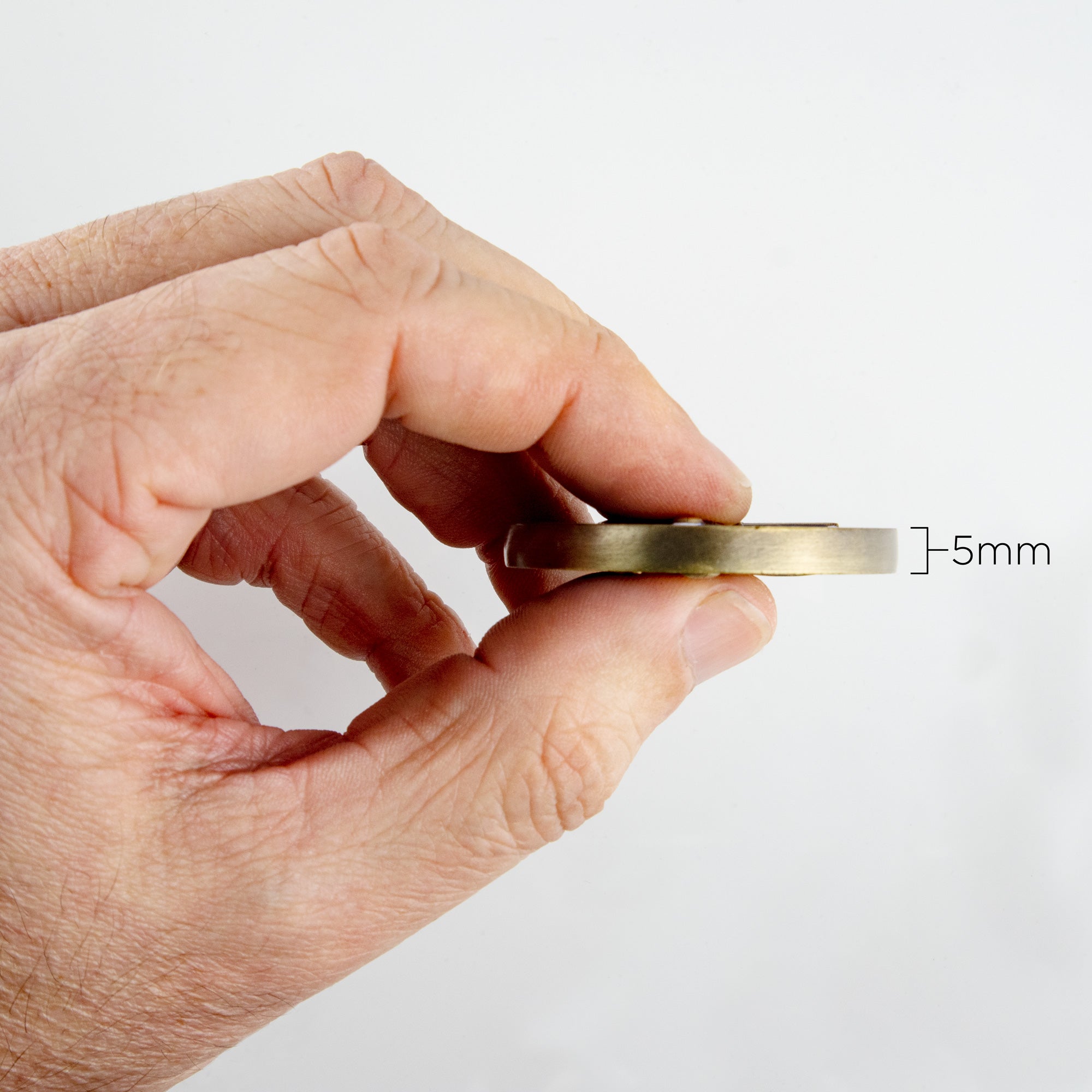 A hand holding the Father's challenge coin, displaying the width of 5mm