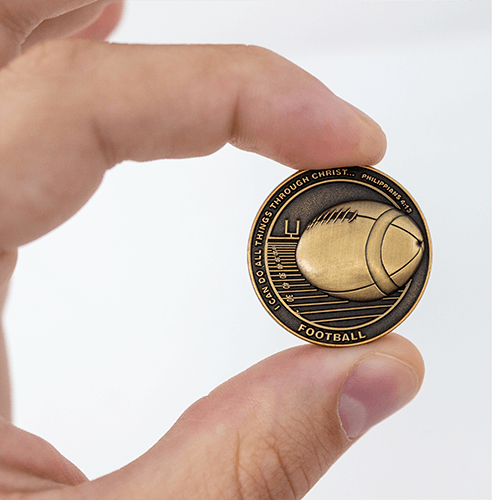 Football Team Antique Gold Plated Sports Coin in between finger showing the front of the coin