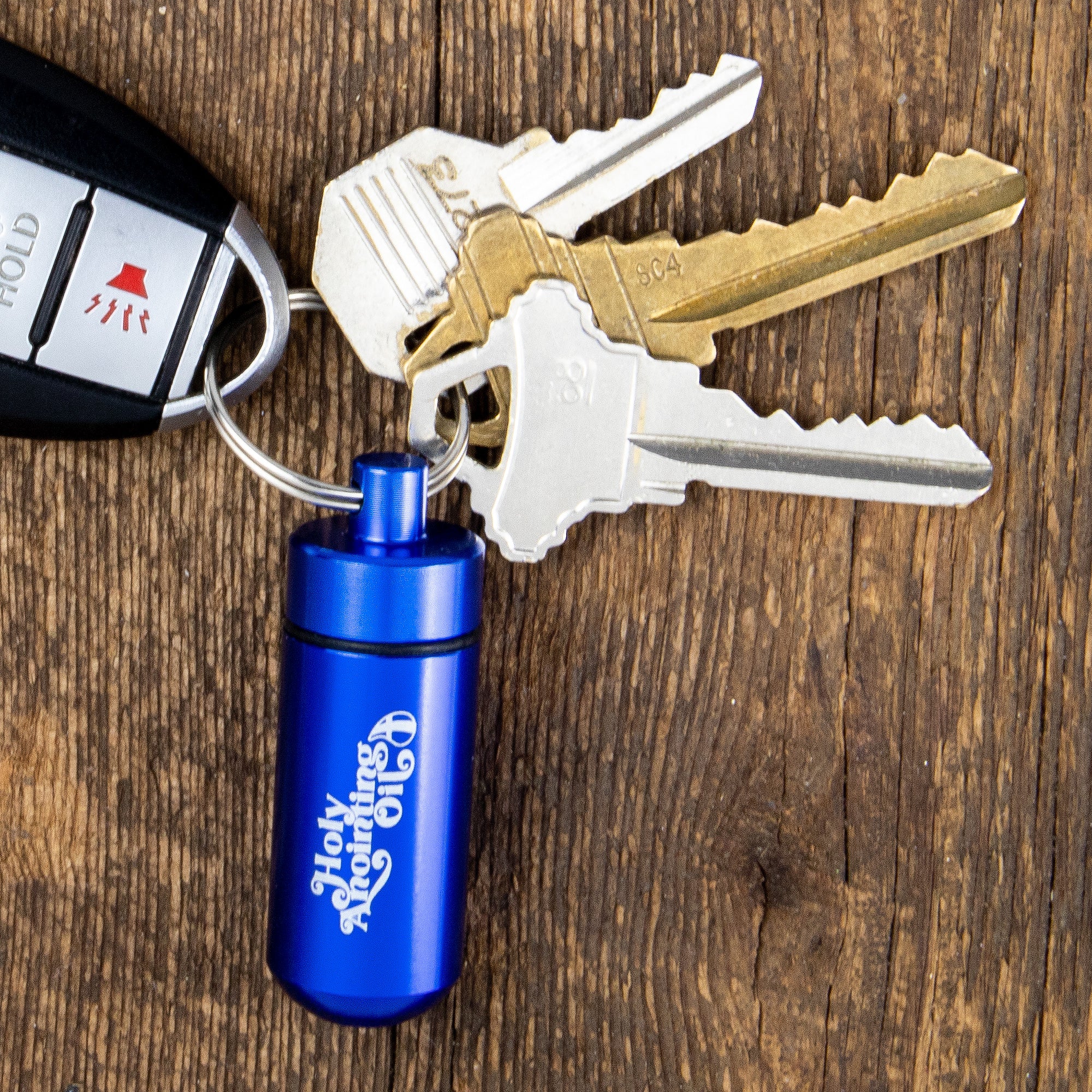Oil Vial Keyring showing keyring vial holder with keys on a wood background