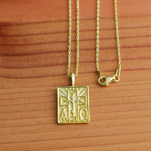 Alpha Omega & St Andrew Cross Gold-Plated Sterling Silver Pendant - 18 Inch Chain on a wooden table