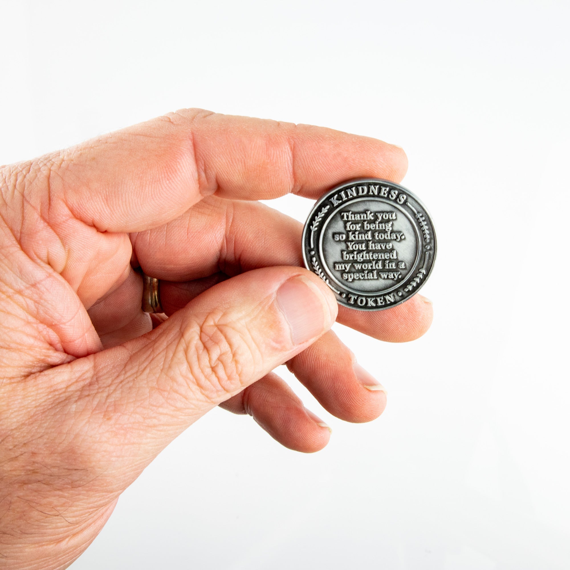 Hand holding Kindness Token showing the front of the coin