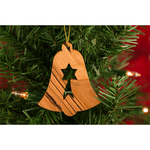 olive wood shooting star bell seasonal ornament hanging on a christmas tree with lights