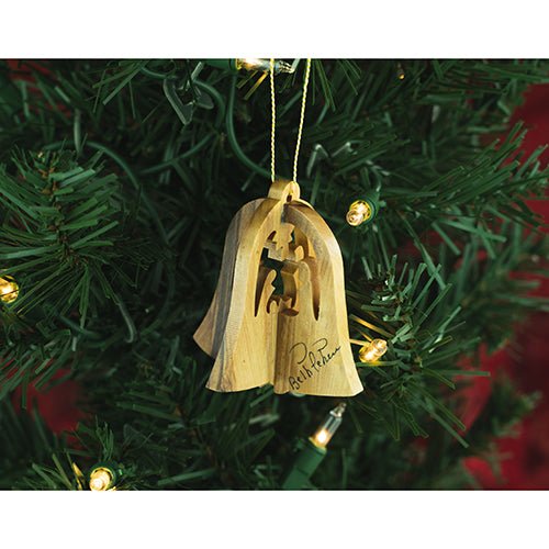 wooden hanging bell nativity ornament on a christmas tree with lights