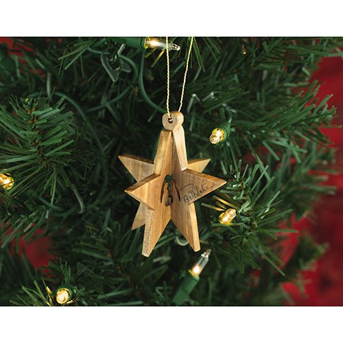 wooden hanging star nativity ornament on a christmas tree with lights